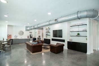 A large living room with couches and a tv in a building with a pipe